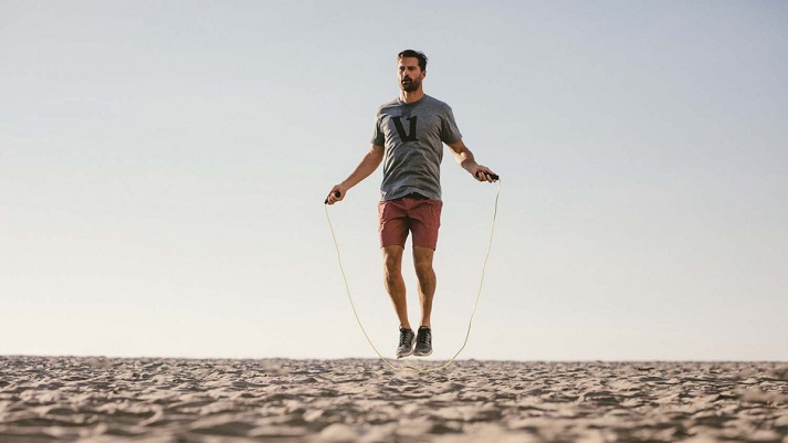 men jumping on rope on the beach