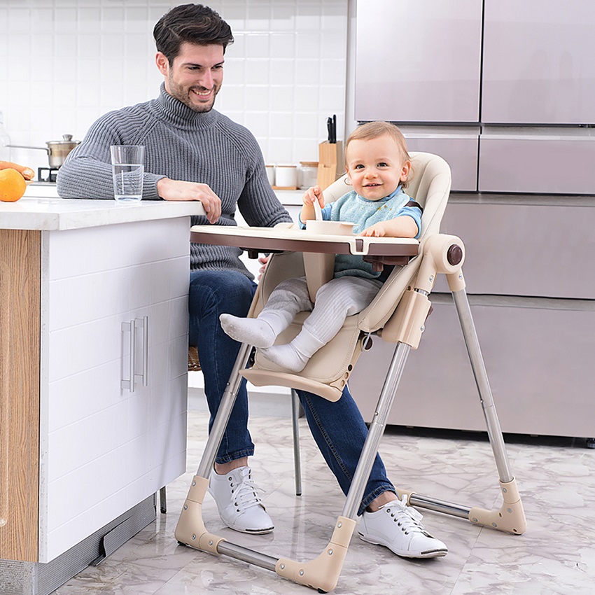 picture of baby sitting in a high chair for toddlers beside a men in the kitchen