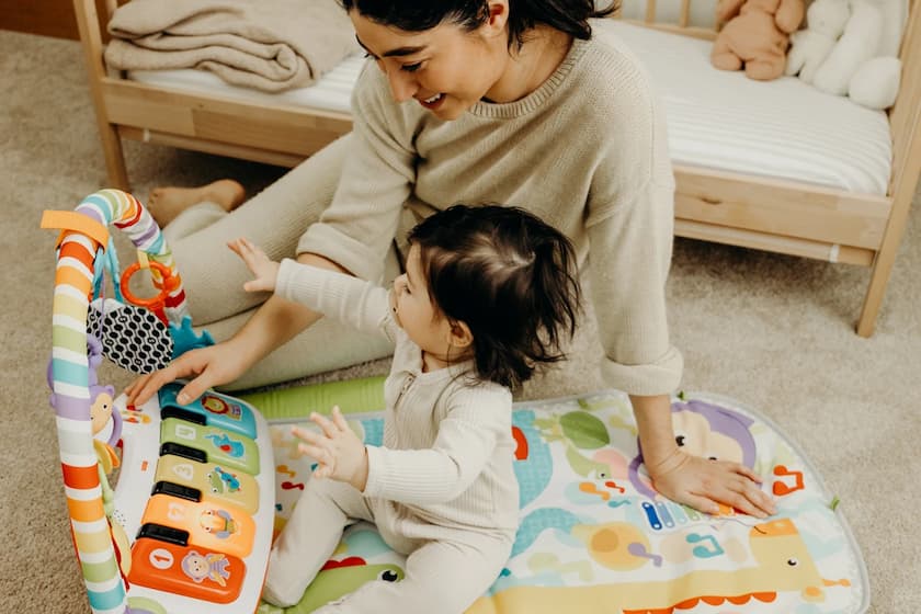 Mom is playing with baby and her toys