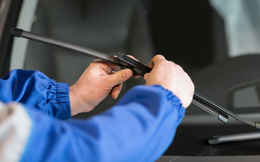 man installing new windscreen wipers