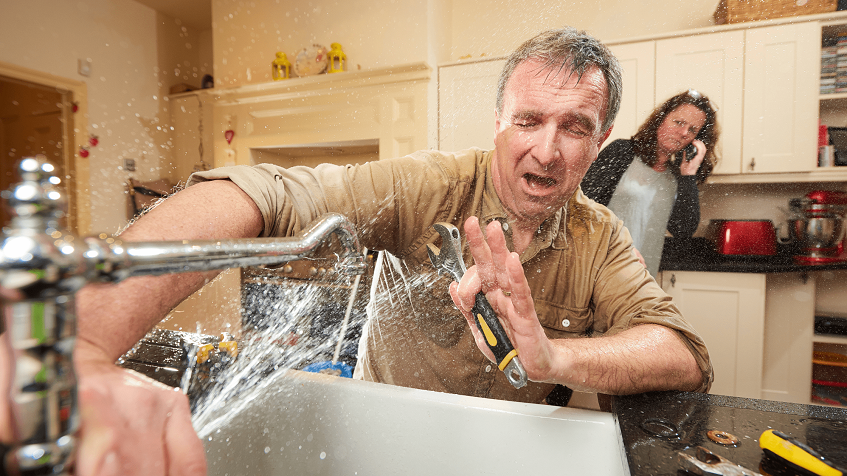 Man trying to fix pipe issue and woman talking on phone at home